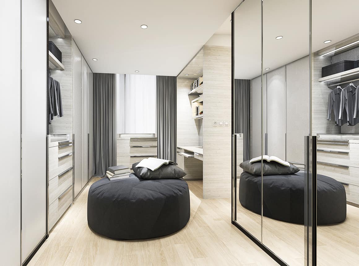 Walk in closet with a chair in the middle of the room and a window on the far wall. Cabinets, handing racks and Aldora glass closet doors cover the other walls.