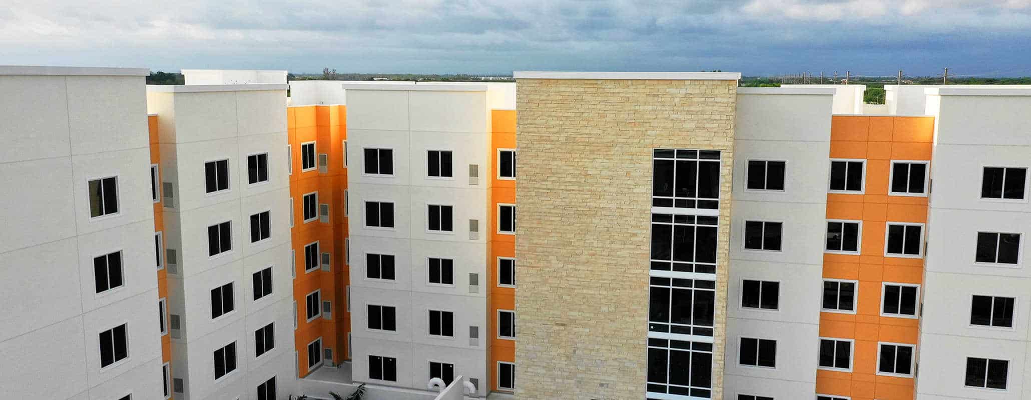 Multi-level orange building with grey outsets and stone accents, FS-300 Impact front set double panel windows with aluminum framing by Aldora, grid curtain wall windows in stone accent section of building
