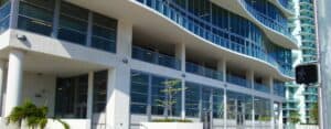 Commercial building entrance, grid SMI-175 impact storefront system windows and doors on multiple levels, curved architectural accents, minimal tropical landscaping in front of building