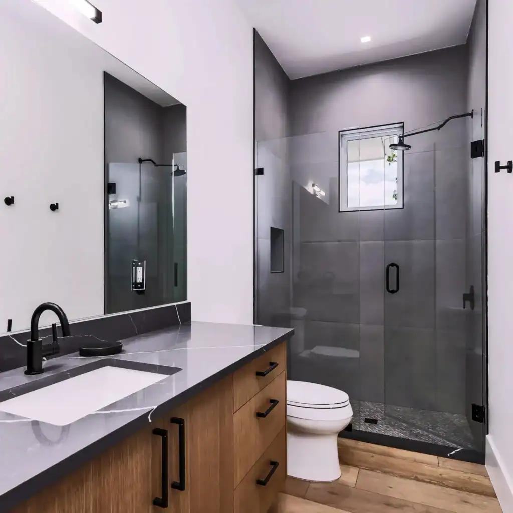 Contemporary bathroom featuring a glass shower, wooden vanity, and minimalist design.
